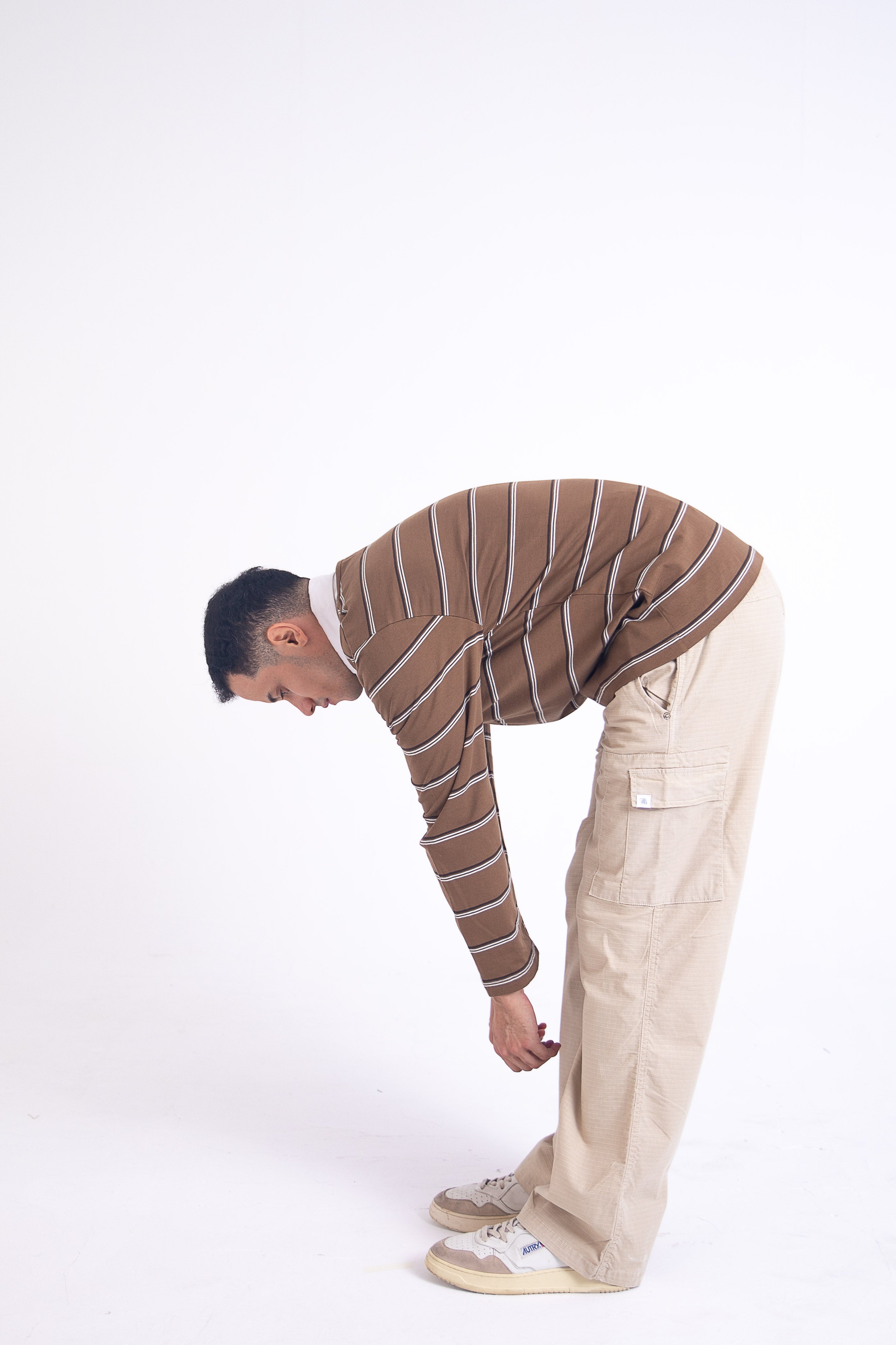 Man in striped sweater and beige ripstop cargo bending over