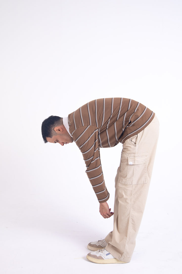 Man in striped sweater and beige ripstop cargo bending over