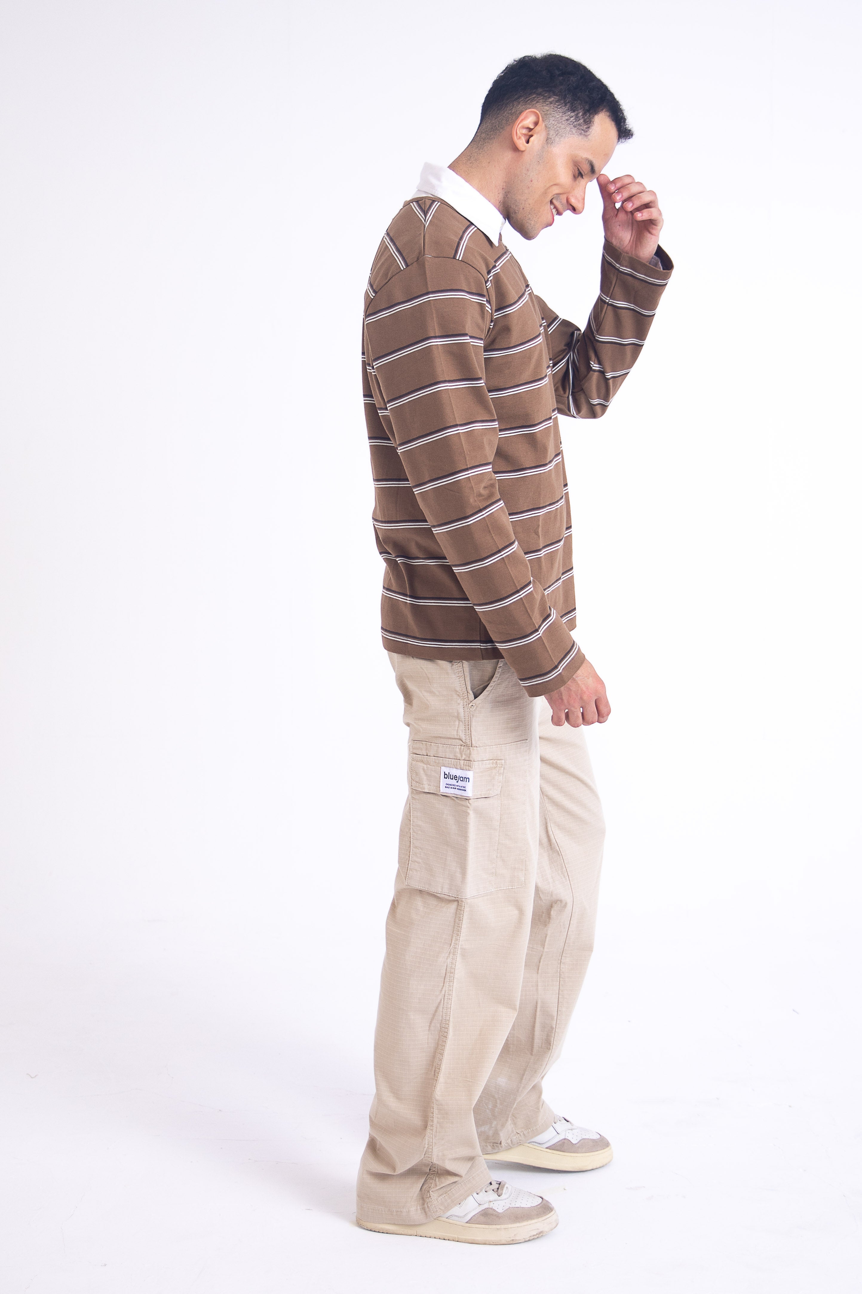 Man wearing a brown striped sweater and beige pants 